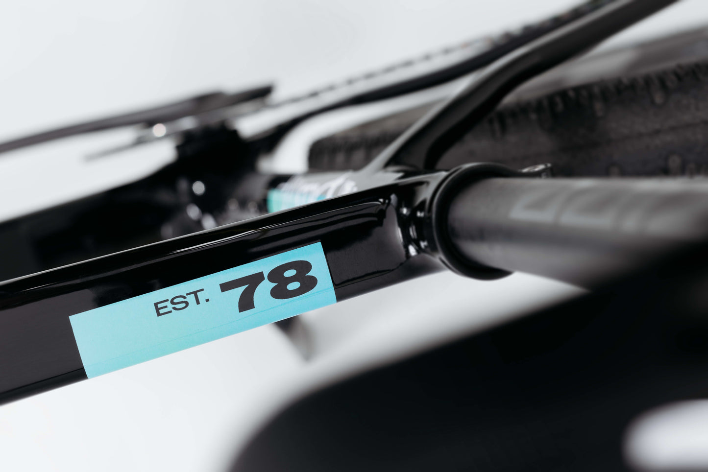 Close-up of a Haro Bikes Buzzard Carbon Frameset “Black Sunrise” with a blue EST. 78 sticker near the rear tire and seat stay.