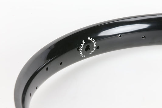 Close-up of a black Premium Varanyak 36H Rim with VARNAR printed on it, designed for ultratechnisches Fahren. The rim has several small holes for spokes along its length, set against a plain white background.