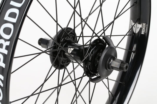 Close-up view of a black wheel hub and spokes, featuring the Curb Cutter Planetary Rear Wheel by Premium. The rim is also black, with partial text showcasing the precision of Signature-Laufräder design.