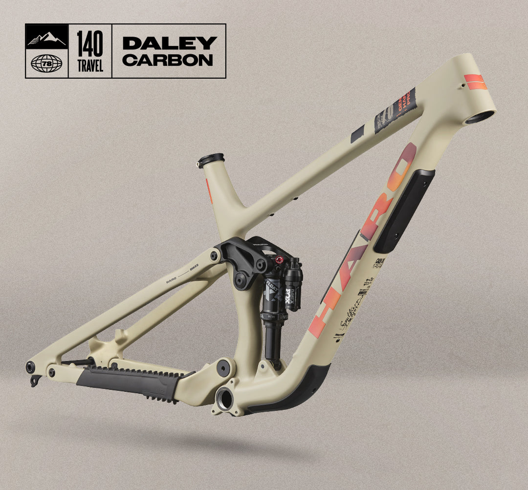 A beige HARO full-suspension mountain bike frame with red accents, labeled “140 Travel” and “DALEY CARBON,” shown against a neutral background.