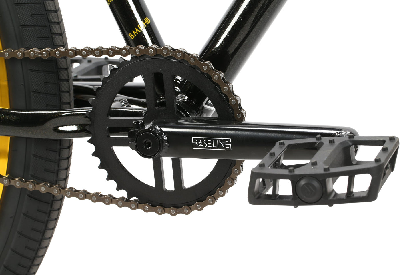 Close-up of a black B.M.F crankset with a chain on a yellow-tired bike, featuring Haro Bikes on the crank arm.