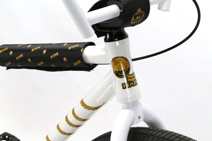 Close-up of a white Haro Bikes B.M.F frame with black and gold details, featuring HARO and a circular emblem. Black handlebar with a gold logo pattern.