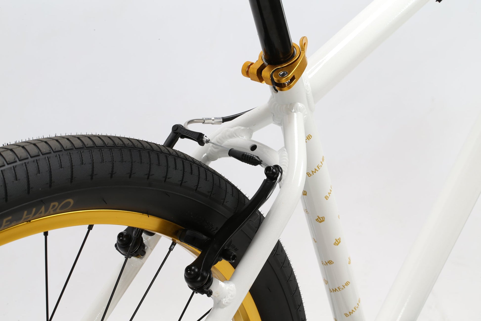 Close-up of the B.M.F by Haro Bikes featuring a white frame, rear tire, gold clamps, and branded BMX components.