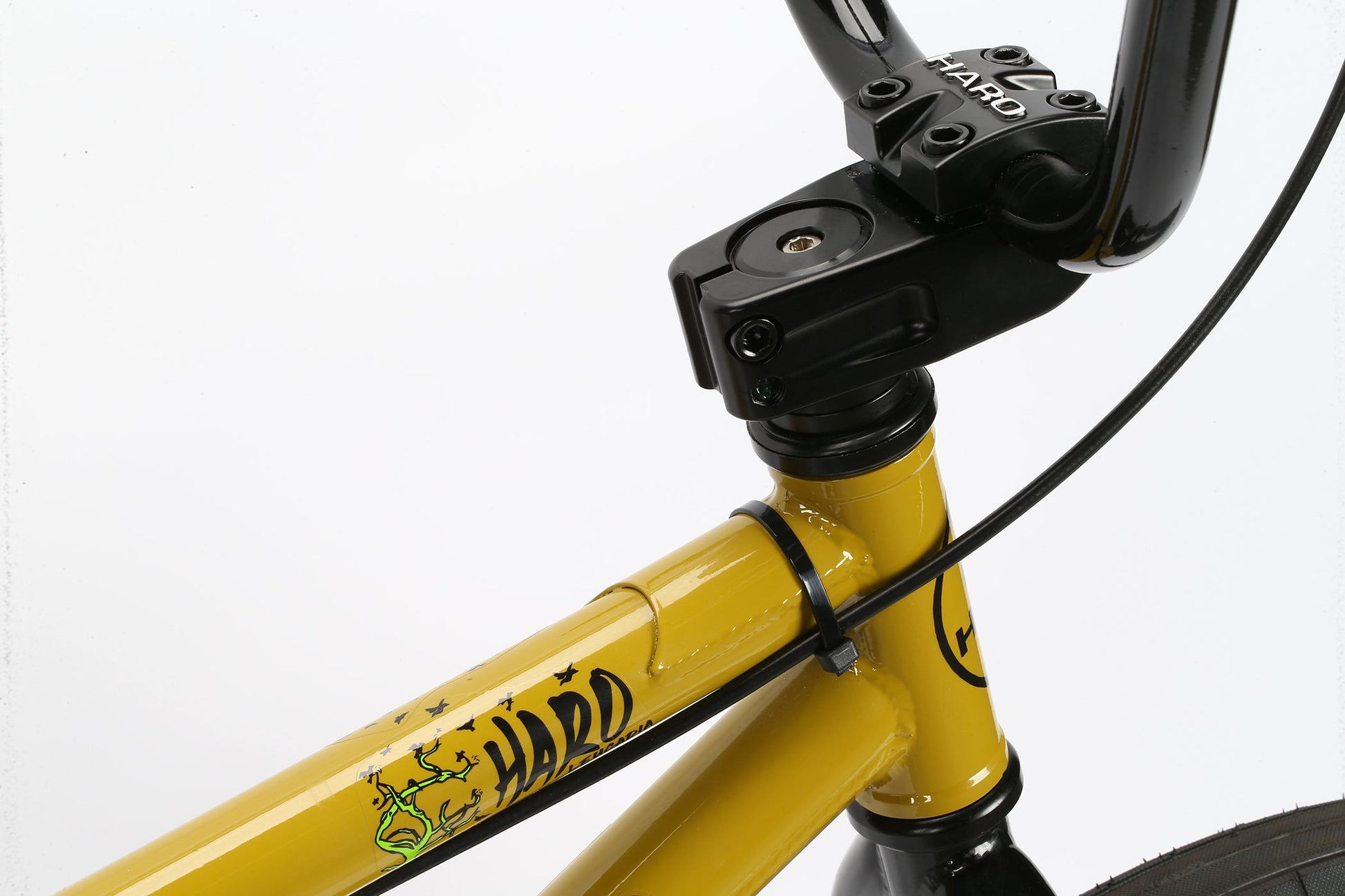 Close-up of a yellow Leucadia BMX bike by Haro Bikes, showing its Hi-Ten steel frame, logo, handlebars, and front wheel.