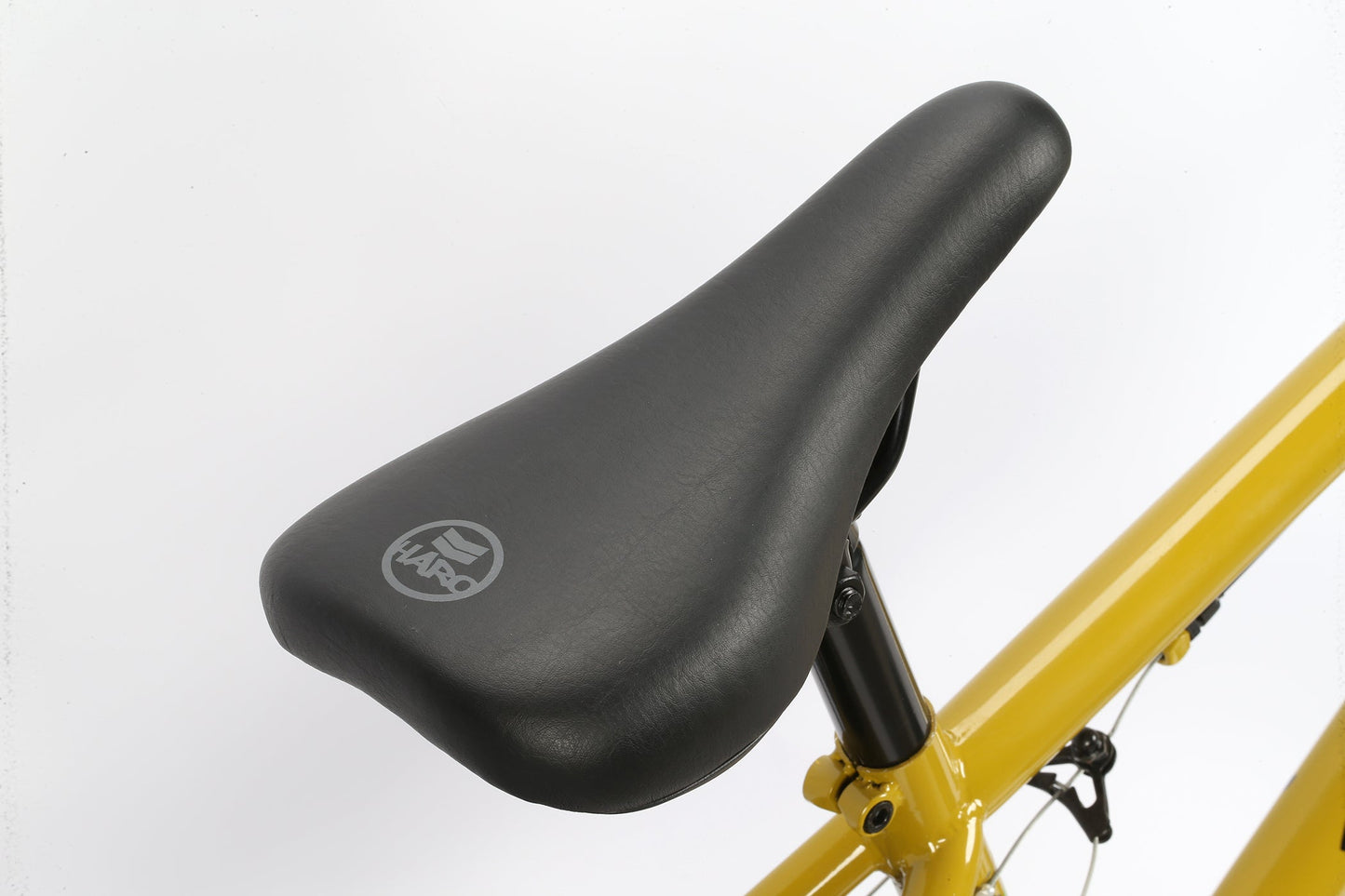 Close-up of a black Leucadia seat with logo on Haro Bikes yellow BMX frame, highlighting a stylisches Fahrrad against a white background.