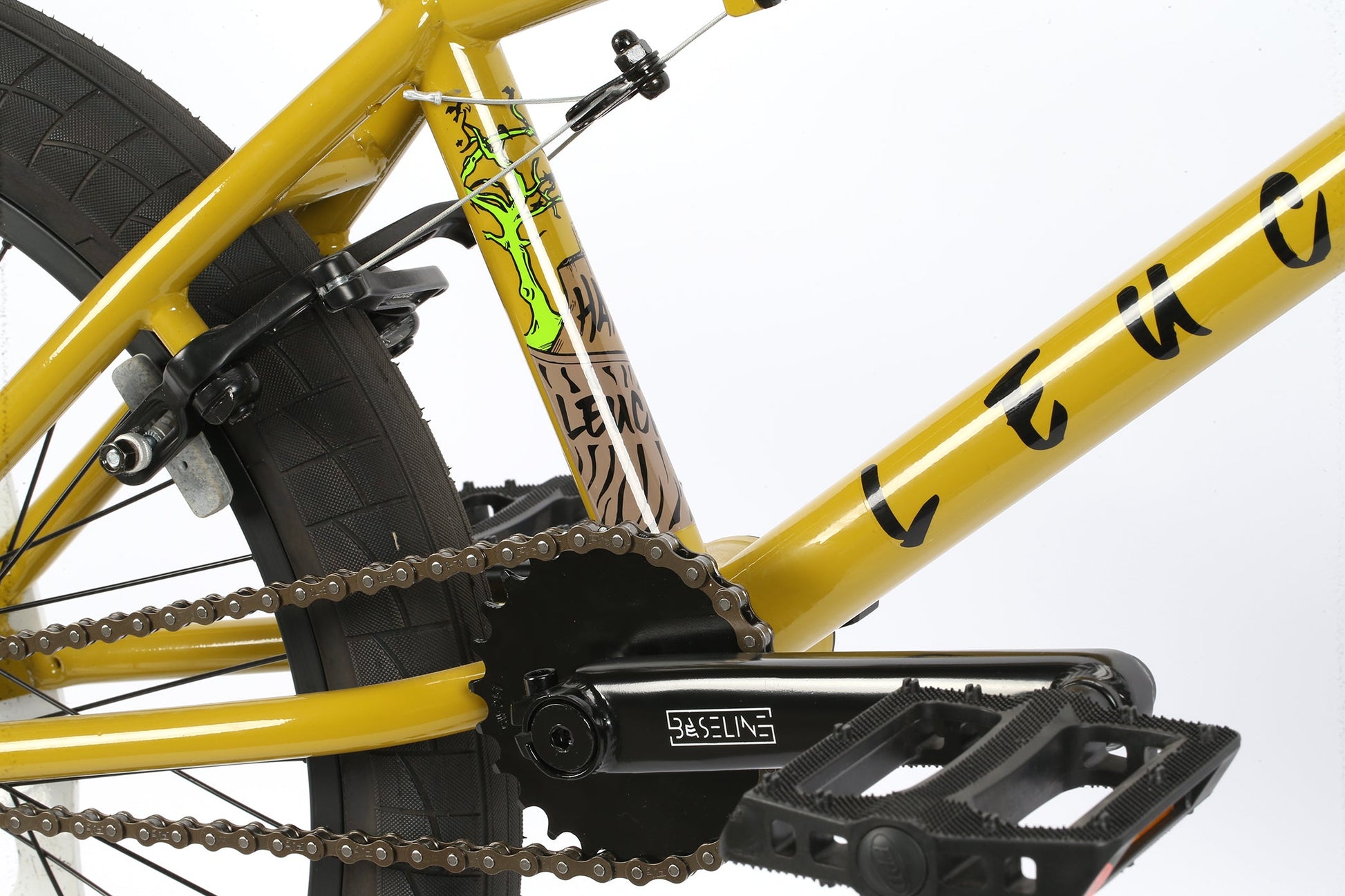 Close-up of the Leucadia BMX bike by Haro Bikes, in yellow with a Hi-Ten steel frame, green graphic design, chain, and pedals.