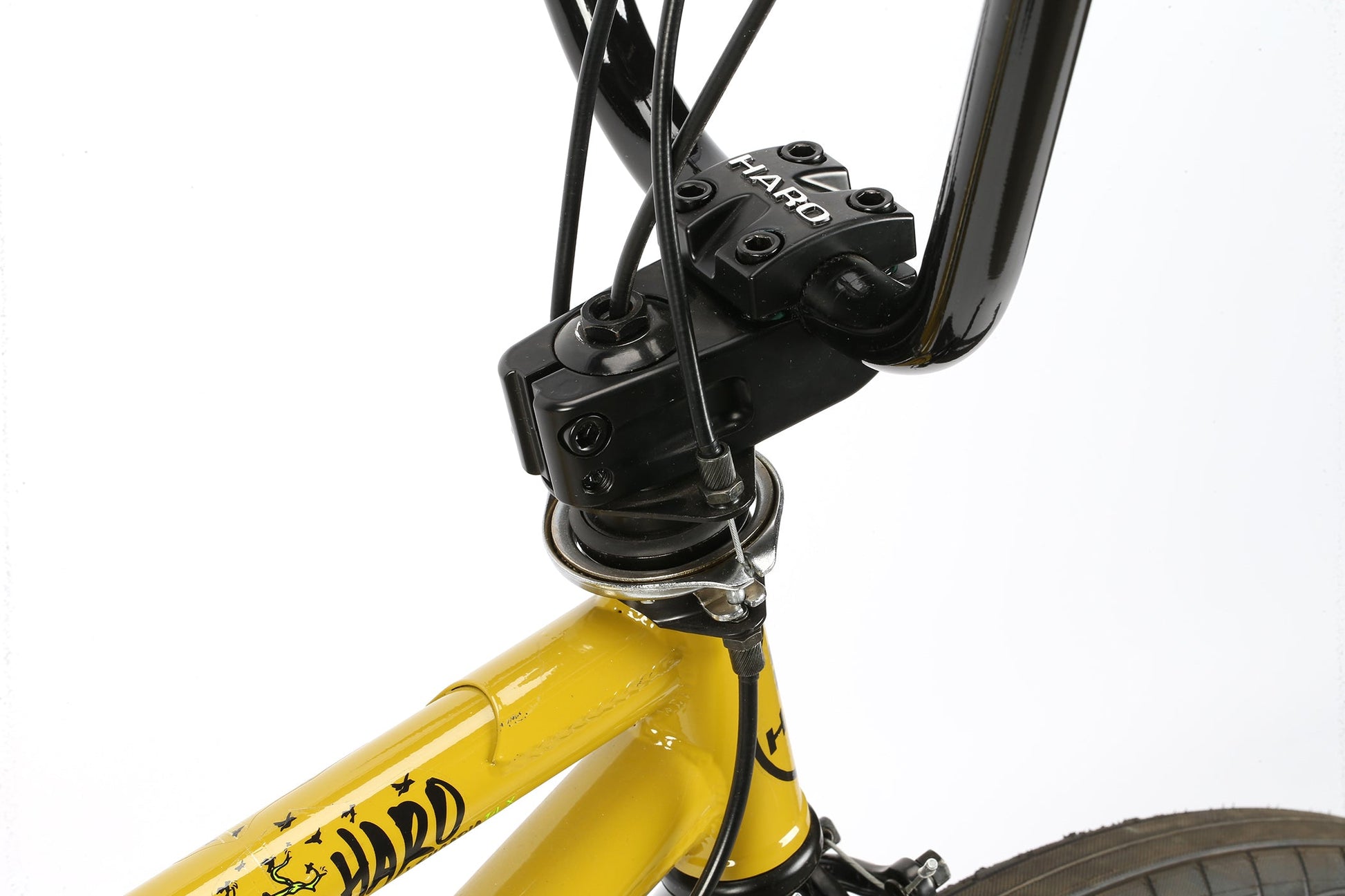 Close-up of Leucadia DLX yellow BMX bikes handlebars and front fork with black cables, Chromoly-Kurbeln, and visible Haro Bikes logo.