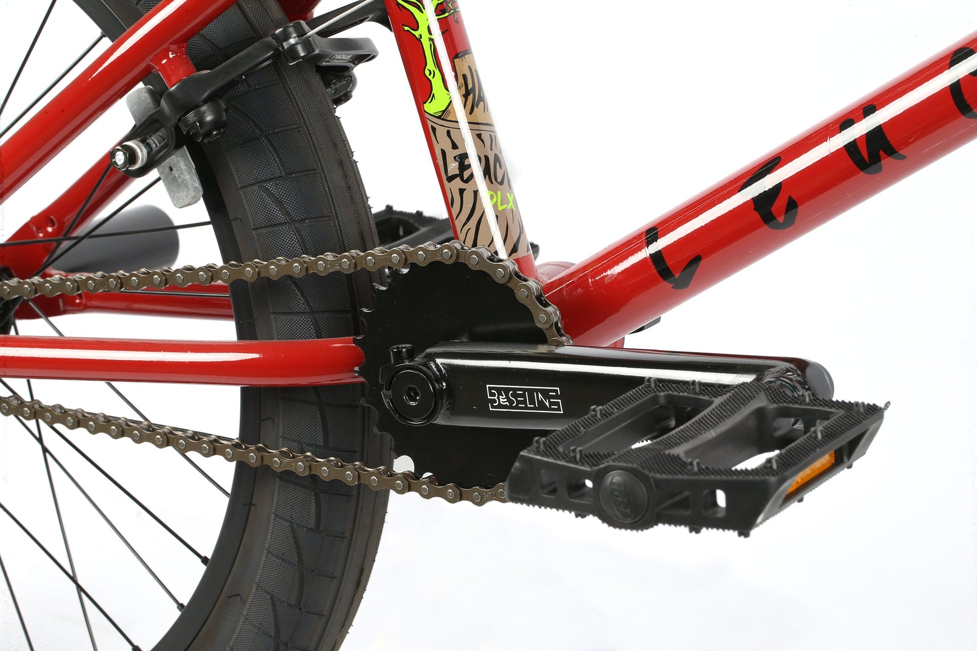 Close-up of a red Leucadia DLX pedal, chain, and rear wheel from Haro Bikes, showcasing detailed metalwork and frame branding.