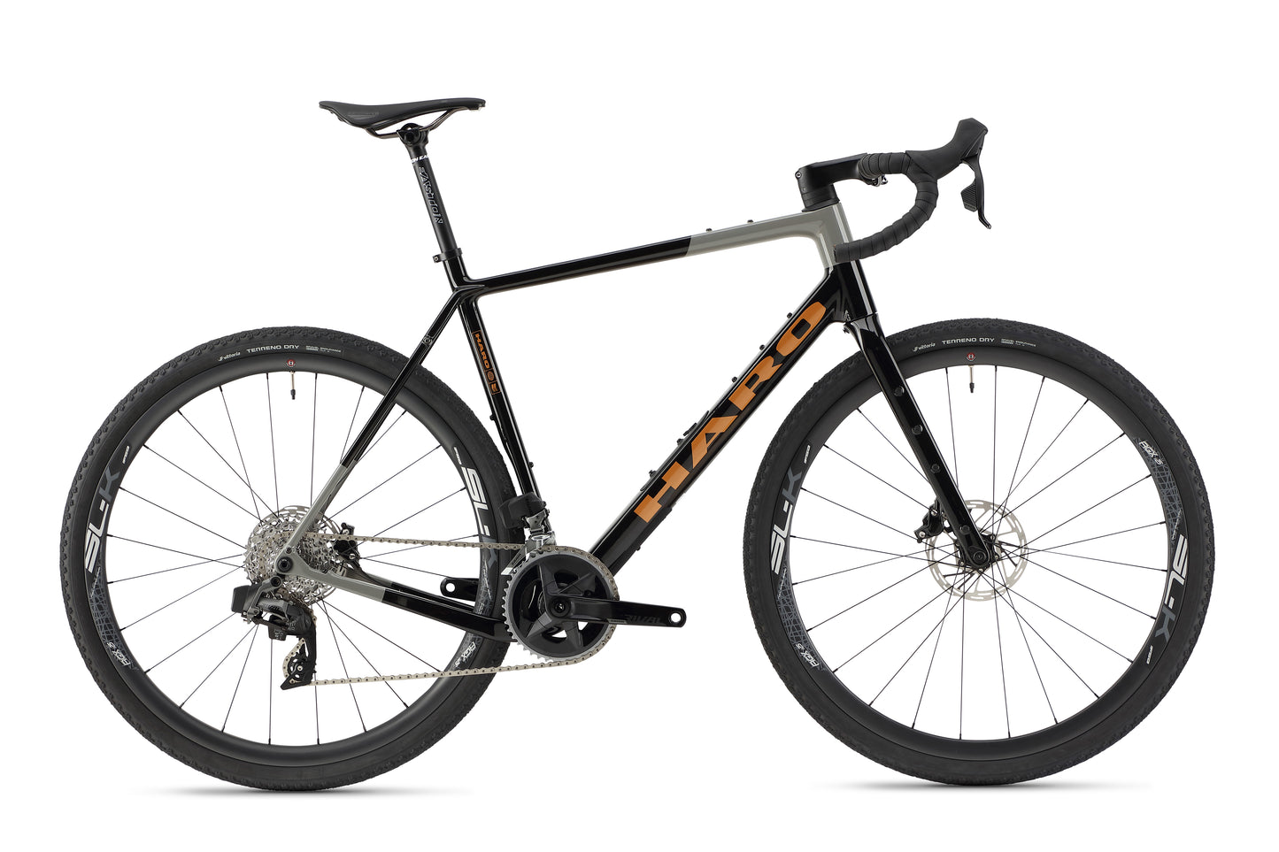 The Buzzard Carbon 1 by Haro Bikes is a black and gray road bike featuring a lightweight carbon frame, drop handlebars, disc brakes, and thick gravel tires for versatility on various terrains.