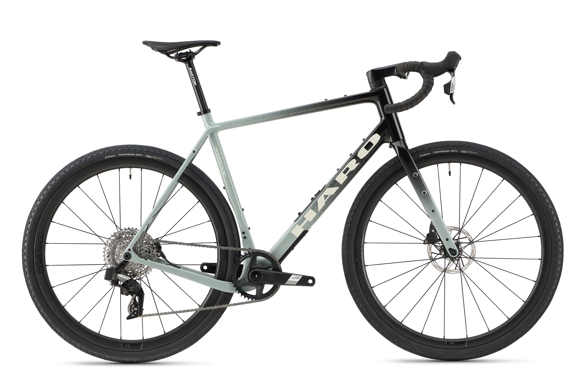 The Buzzard Carbon 2 by Haro Bikes is a sleek gravel bike with a light grey carbon frame, black accents, and drop handlebars. It features disc brakes and wide tires, highlighted by the SRAM Apex components and the brand logo. Presented on a plain white background.