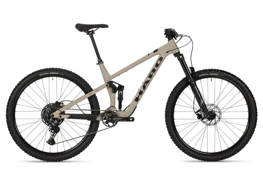 Side view of a beige Daley Alloy 3 Trail-Bike by Haro Bikes, featuring a full suspension aluminum frame, knobby tires, black seat and handlebars. The All-Mountain-29er is equipped with disc brakes and gear system, positioned on a white background.