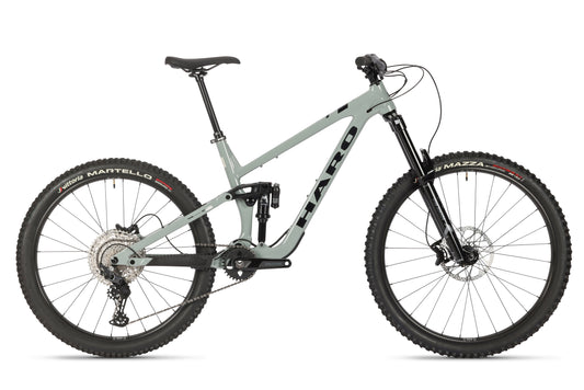 The Greer Alloy 2 from Haro Bikes is a green mountain bike featuring a full suspension alloy frame, disc brakes, and a black seat. With its large knobby tires in mullet configuration, its ideal for rough terrain.