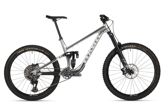 The Haro Bikes Greer Alloy LTD 1 is a gray mountain bike with a durable frame and thick black Martello and Mazza tires. Featuring visible Fox Suspension components, its designed for off-road cycling with a sleek, modern appearance.