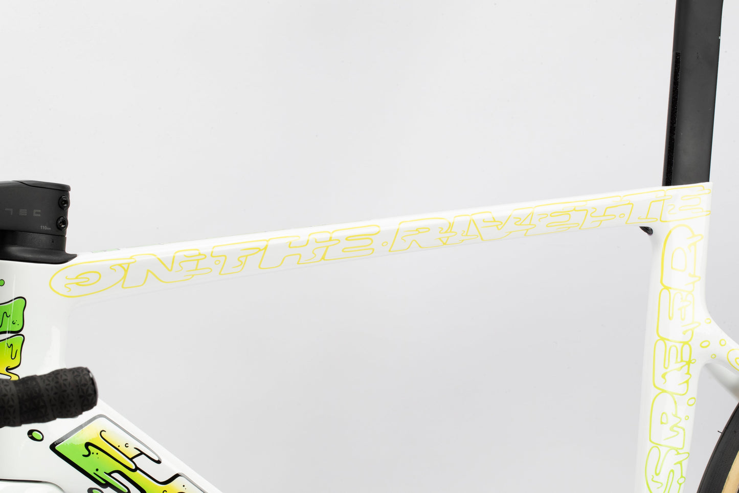 Close-up of a Haro Bikes Rivette Carbon LTD frame featuring ON THE RIVET in yellow on white. As part of Mark Wards limited edition, it boasts abstract green and yellow designs, including the handlebar and seat post.