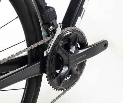 Close-up of the Rivette Carbon 2s sleek black crankset and chainring, featuring a high-pitch carbon fiber chain and derailleur. The shiny components from Haro Bikes highlight its quality materials and modern design with internal cable routing.