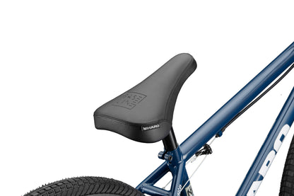 A close-up of a black seat on a blue Haro Bikes Downtown 24 BMX with 24 Zoll Laufräder, part of the rear tire in view.