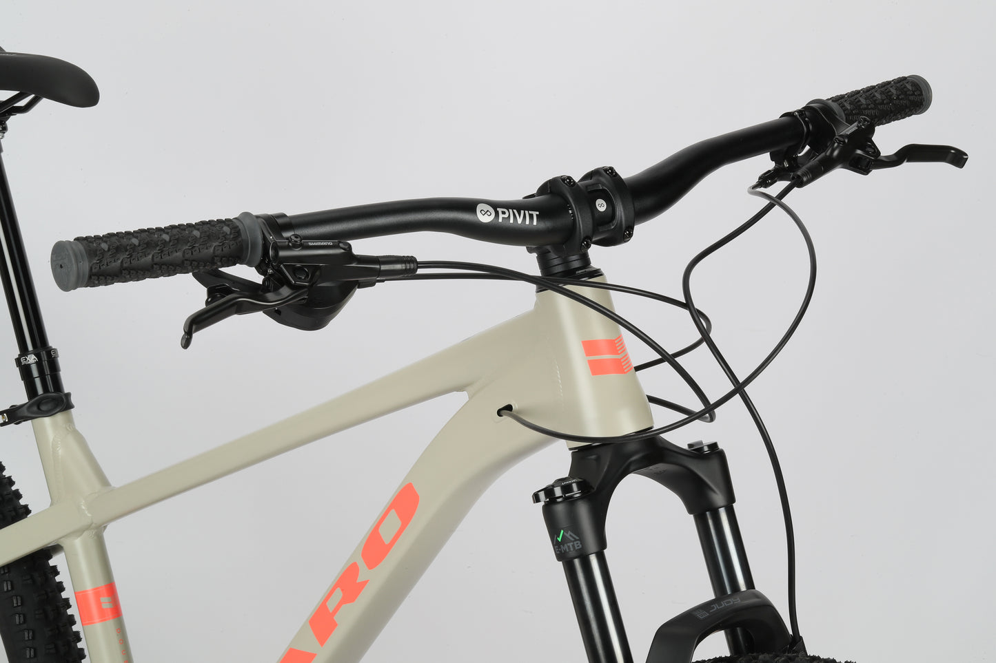 Close-up of Haro Bikes Double Peak 1 with orange-accented handlebars and front suspension on its light beige frame.