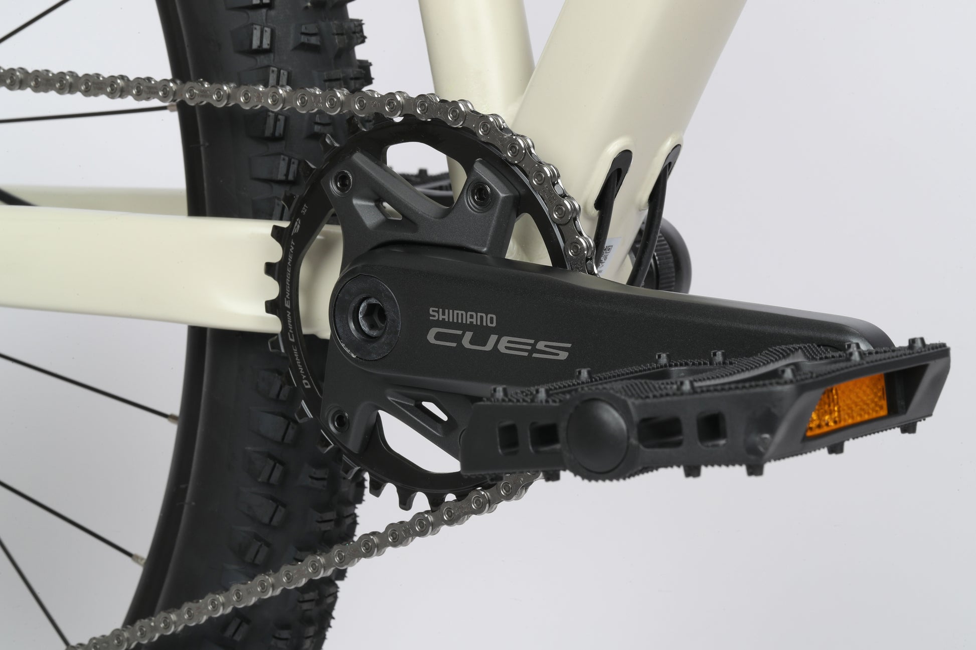 Close-up of Haro Bikes Double Peak 1 drivetrain, featuring Shimano Cues crankset and pedal, knobby tire, and Shimano Hydraulic Disc Brakes.