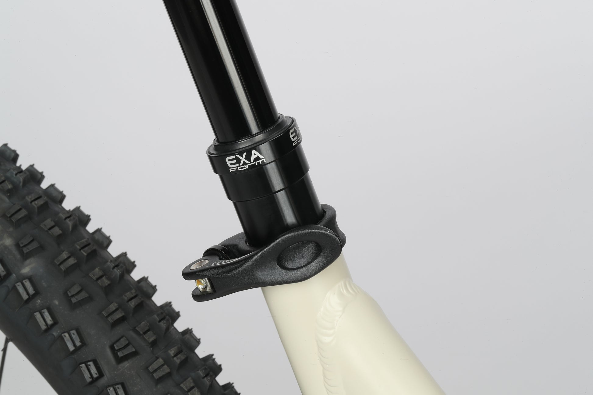 Close-up of a Haro Bikes Double Peak 1 with an EXA seatpost clamp contrasting against its light frame on a plain backdrop.