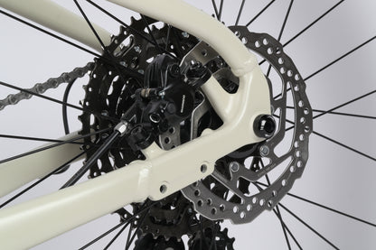 Close-up of the Double Peak 1s Shimano hydraulic disc brakes and gear components on a light beige frame by Haro Bikes.