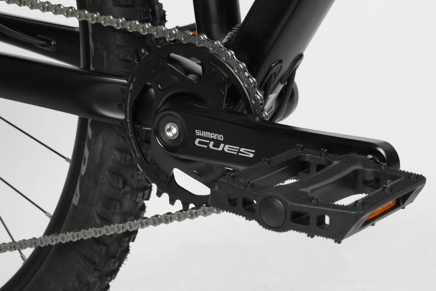 Close-up of the black Shimano CUES crankset on a Double Peak 2 mountain bike by Haro Bikes with an aluminum frame, tire, and metal chain.