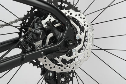 Close-up of Double Peak 2s rear disc brake and wheel with visible gears on an Aluminiumrahmen by Haro Bikes, set against a plain background.