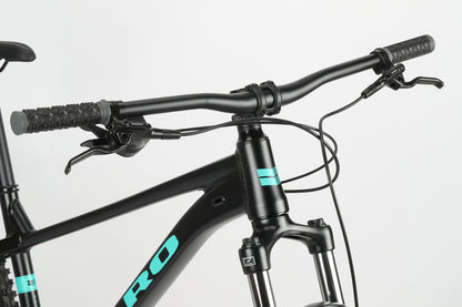 Close-up of the sleek Double Peak 3 handlebar by Haro Bikes with teal accents, dual brake levers, and a visible suspension fork.