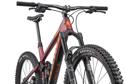 Close-up of the Haro Bikes Daley Carbon 1 trailbike with thick tires, front suspension, and a matte maroon and orange carbon frame.