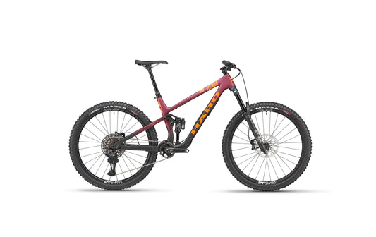 The Haro Bikes Daley Carbon 1 is a red-orange carbon trail bike with wide knobby tires and black components, shown on white.