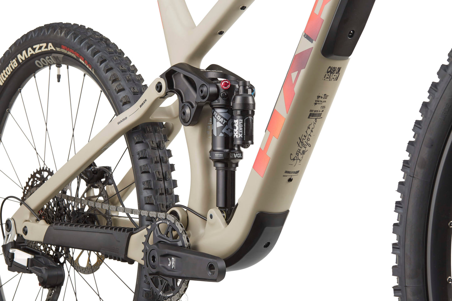 Close-up of the Haro Bikes Daley Carbon 3’s rear suspension, crank arm, chain, and knobby-tired rear wheel.