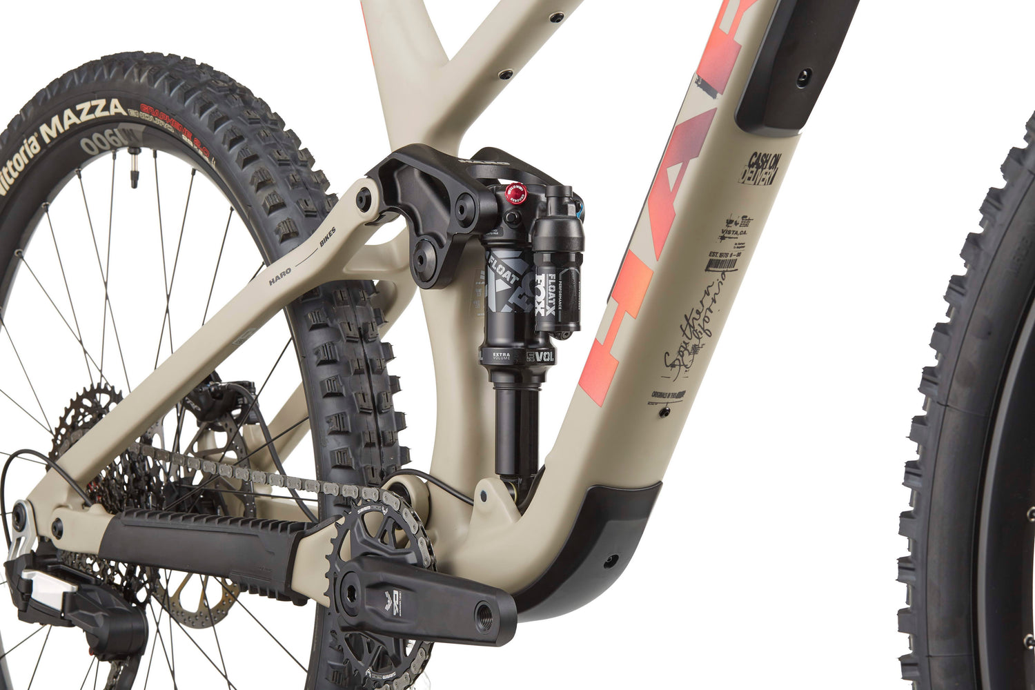 Close-up of the Haro Bikes Daley Carbon 3’s rear suspension, crank arm, chain, and knobby-tired rear wheel.