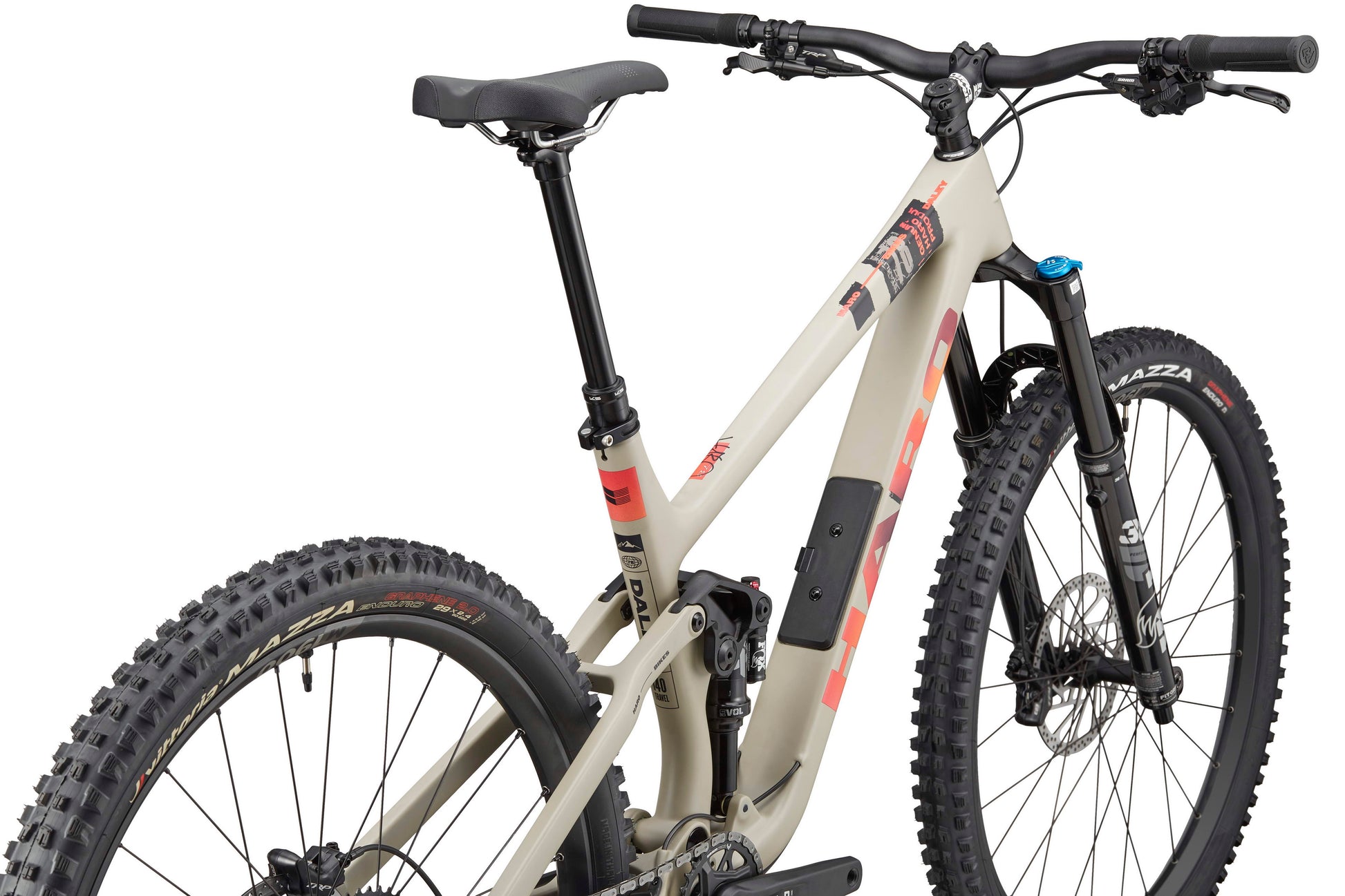 The Haro Bikes Daley Carbon 3 is a beige all-mountain carbon bike with red accents and thick knobby tires, seen from the rear side.