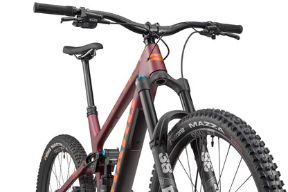 Close-up of the Haro Bikes Greer Carbon 1 Enduro with Fox suspension, thick tires, and a maroon frame from a low front angle.