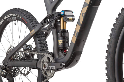 Close-up of a Haro Bikes Greer Carbon Top Shelf’s rear suspension, FOX shock, XTR crankset, and tire on this carbon mountain bike.