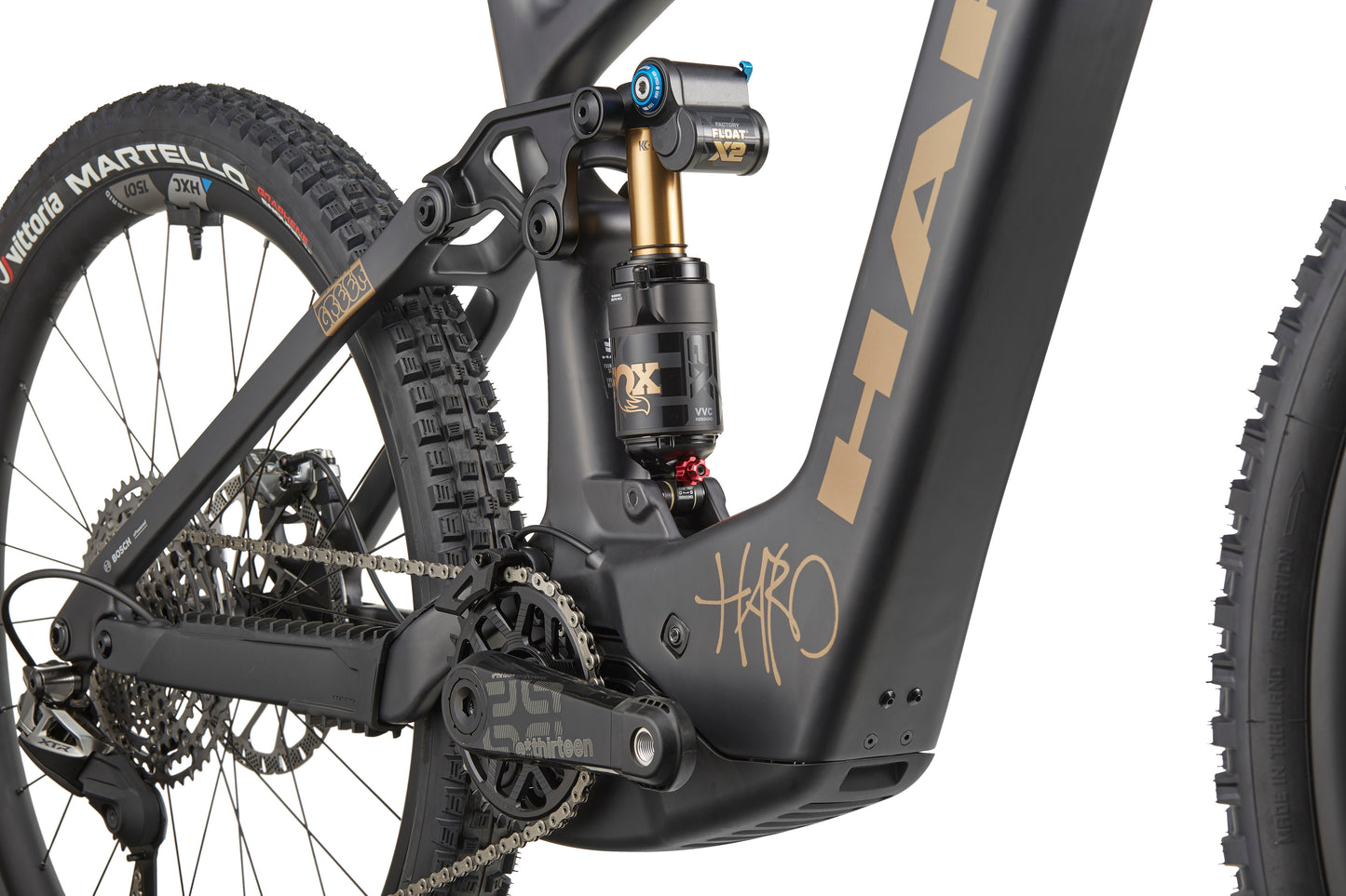 Close-up of a Haro Bikes eGreer Carbon Top Shelf E-Bike's rear suspension, drivetrain, and tire on matte black carbon frame with Bosch CX.