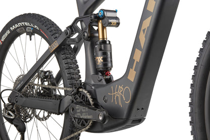 Close-up of a Haro Bikes eGreer Carbon Top Shelf E-Bike's rear suspension, drivetrain, and tire on matte black carbon frame with Bosch CX.