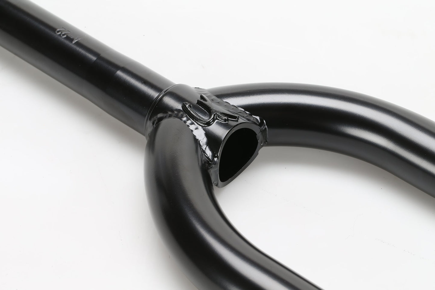 A close-up of Premiums CK V2 Fork, a black metal bicycle fork crafted from Chromoly-Stahlrohr, against a white background highlights its joint and elegant curved shape.