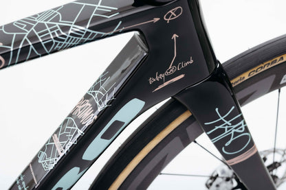 Close-up of a Haro Bikes Partimos Carbon Frameset “Grid” front frame, wheel, abstract lines, and “takywe climb” text.