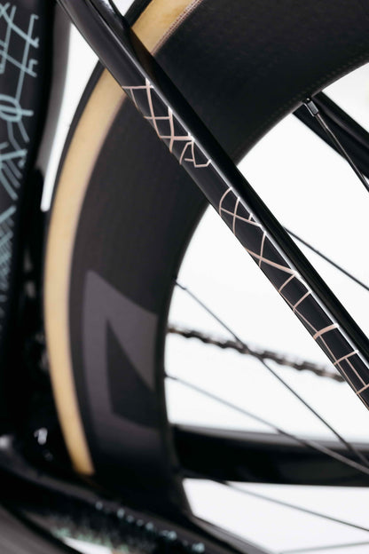Close-up of Haro Bikes' Partimos Carbon Custom "Grid" rear wheel, tan sidewall tire, and geometric frame patterns.
