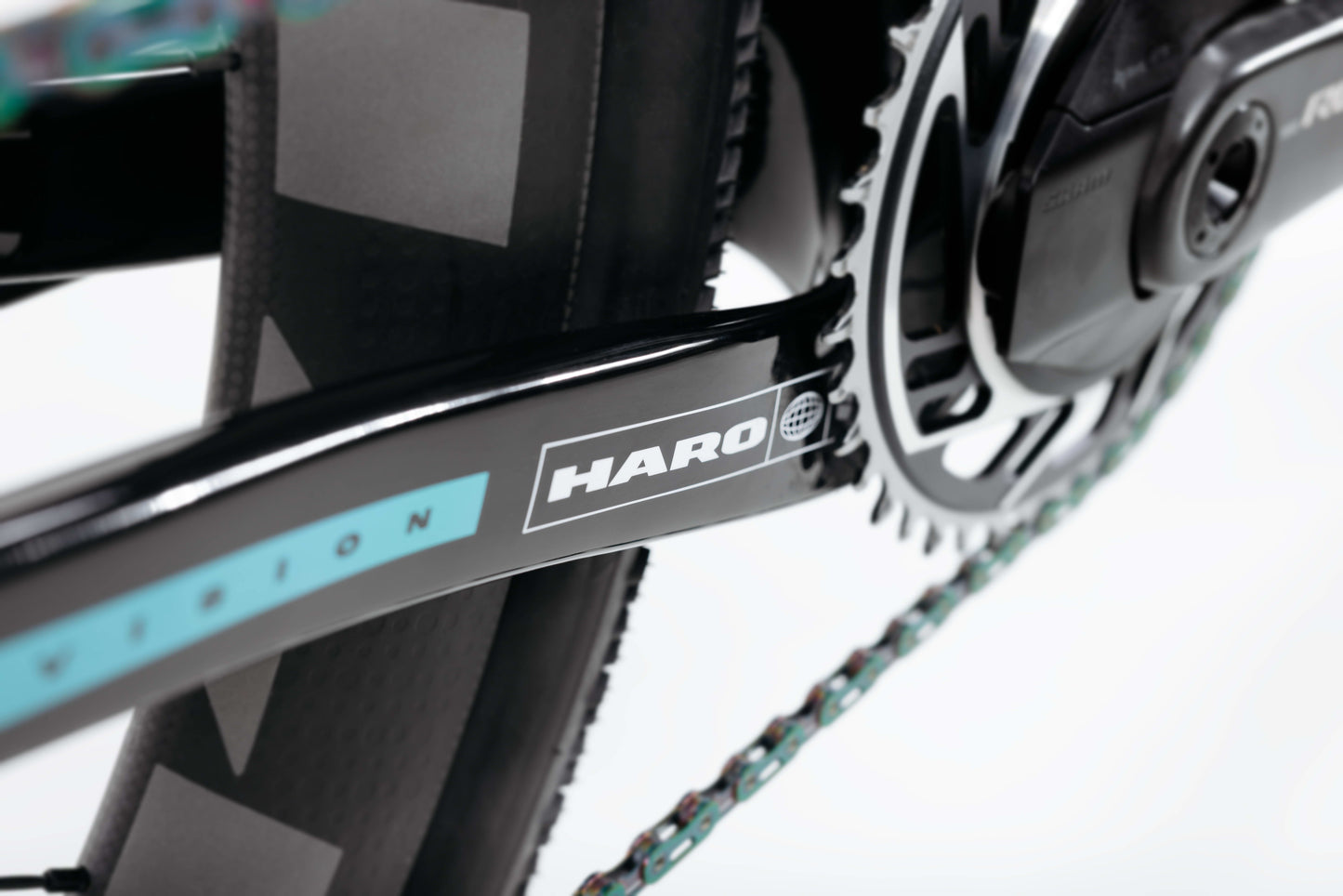 Close-up of a black Haro Bikes crank arm on the Buzzard Carbon Frameset “Black Sunrise,” plus chainring and rear wheel visible.