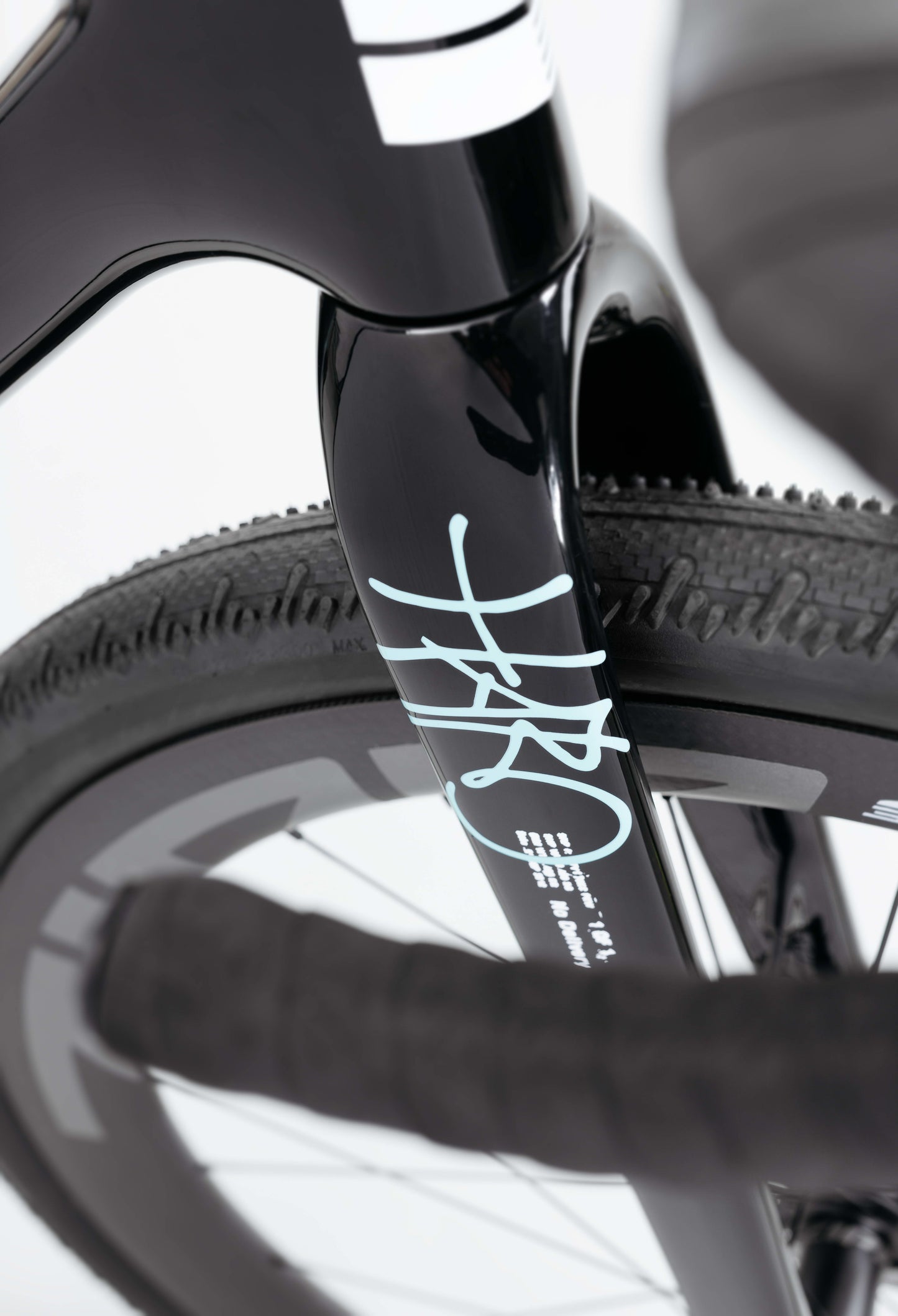 Close-up of the Haro Bikes Buzzard Carbon Frameset “Black Sunrise” fork, with white accents, textured tire, and partial handlebar visible.