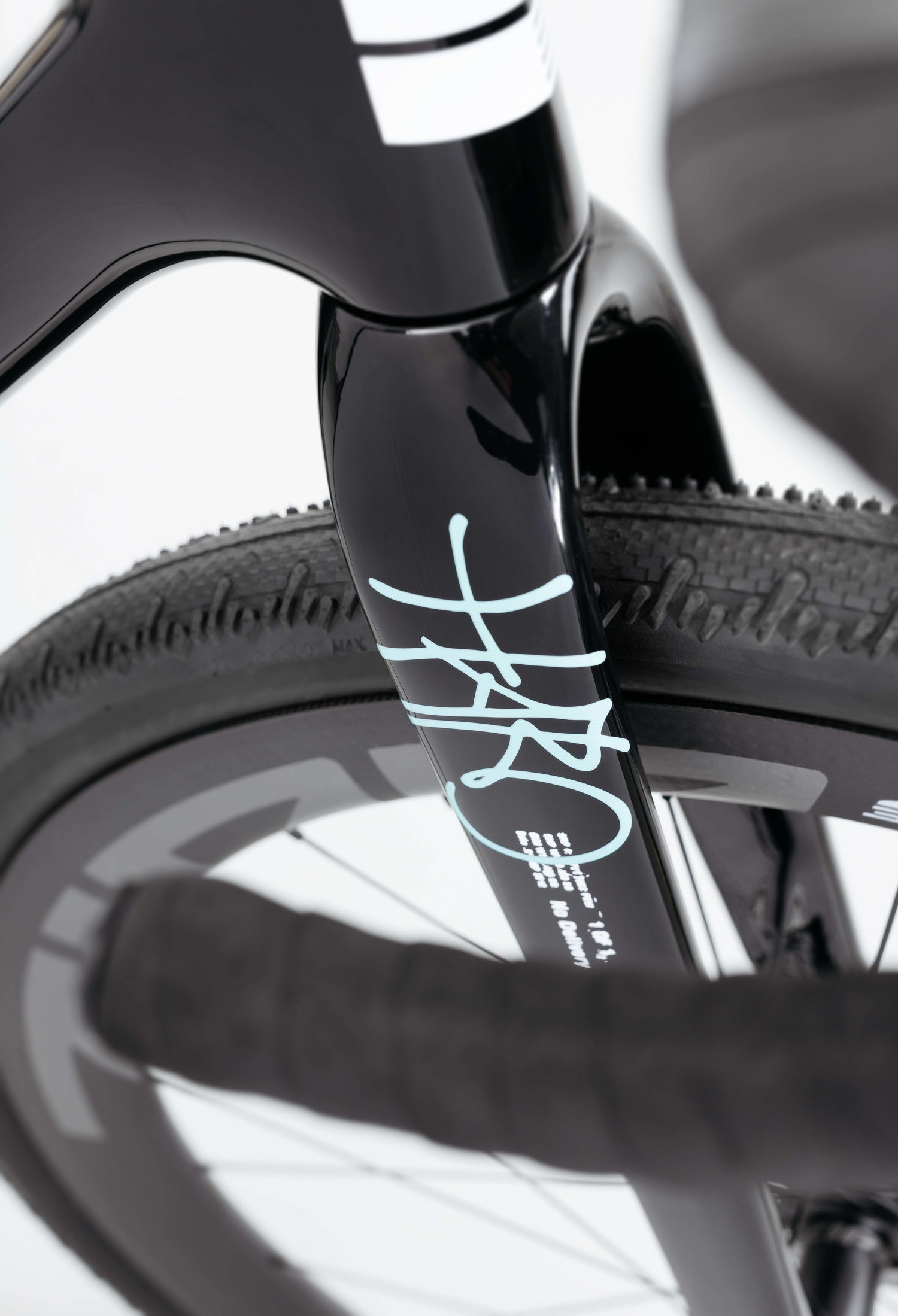 Close-up of the Haro Bikes Buzzard Carbon Frameset “Black Sunrise” fork, with white accents, textured tire, and partial handlebar visible.
