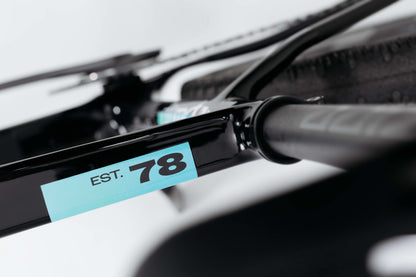 Close-up of a Haro Bikes Buzzard Carbon Frameset “Black Sunrise” with a blue EST. 78 sticker near the rear tire and seat stay.