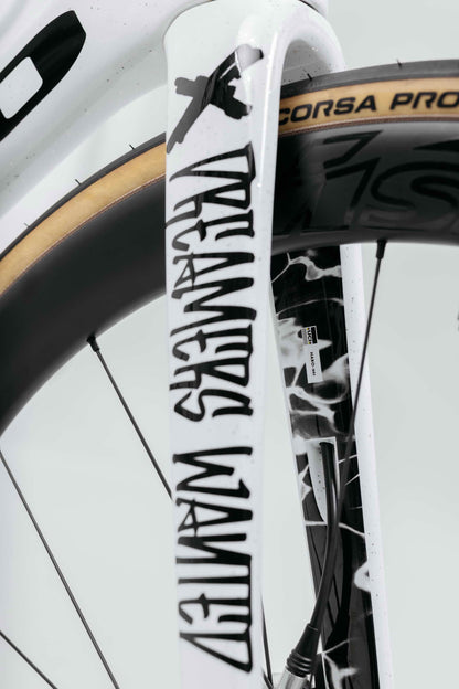 Close-up of a white Haro Bikes Partimos Carbon Custom "Black Sheep" fork with text, plus part of a Pirelli Corsa Pro tire shown.
