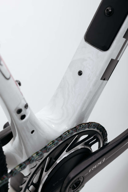 Close-up of Haro Bikes’ Buzzard Carbon Custom “Desert Sunset” gravel frame, chainring, and crank arm with a clean, modern design.