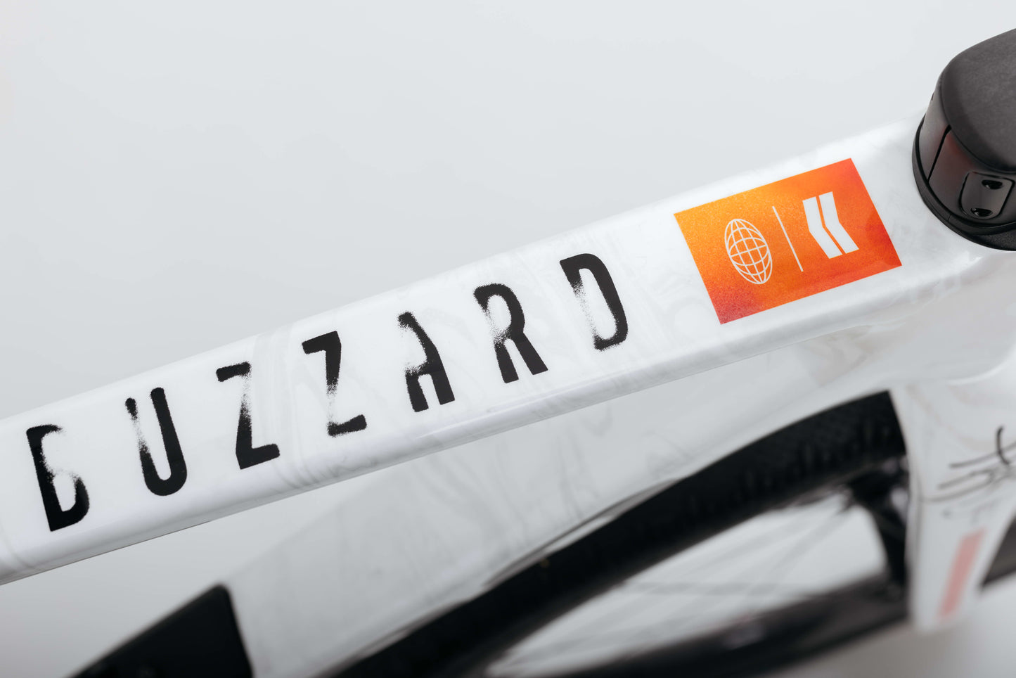Close-up of a Haro Bikes Buzzard Carbon Custom “Desert Sunset” with an orange sticker featuring a globe and arrow icon.