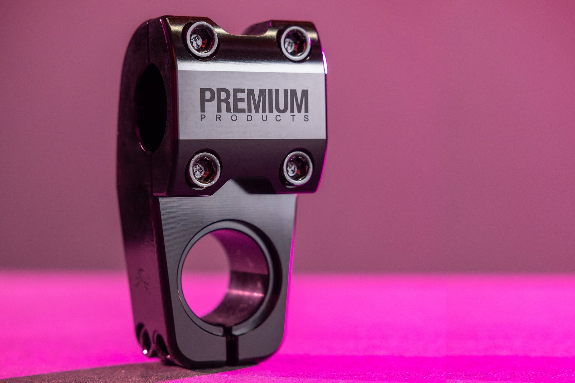 A black Premium CK Top Load Stem V3 stands upright on a pink surface with a pink background.