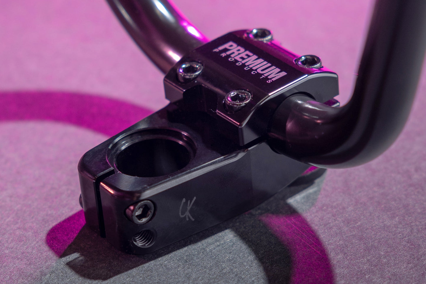 Close-up of a black Premium CK Top Load Stem V3 BMX stem and handlebars under pink light, featuring PREMIUM branding on the stem.