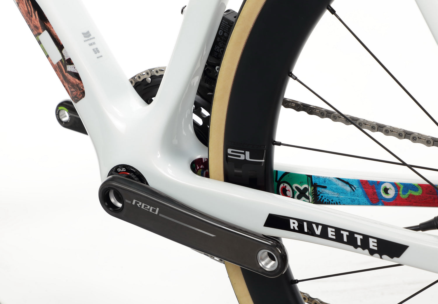 Close-up of a white Haro Bikes Rivette Carbon EP Edition frame with colorful graphics, plus parts of the pedal and chain.