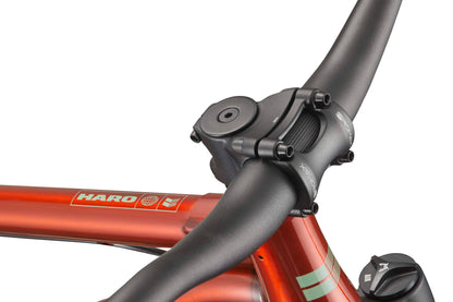 Close-up of a black handlebar and stem on an orange HARO Steel Reserve TS, showing branding and frame details.
